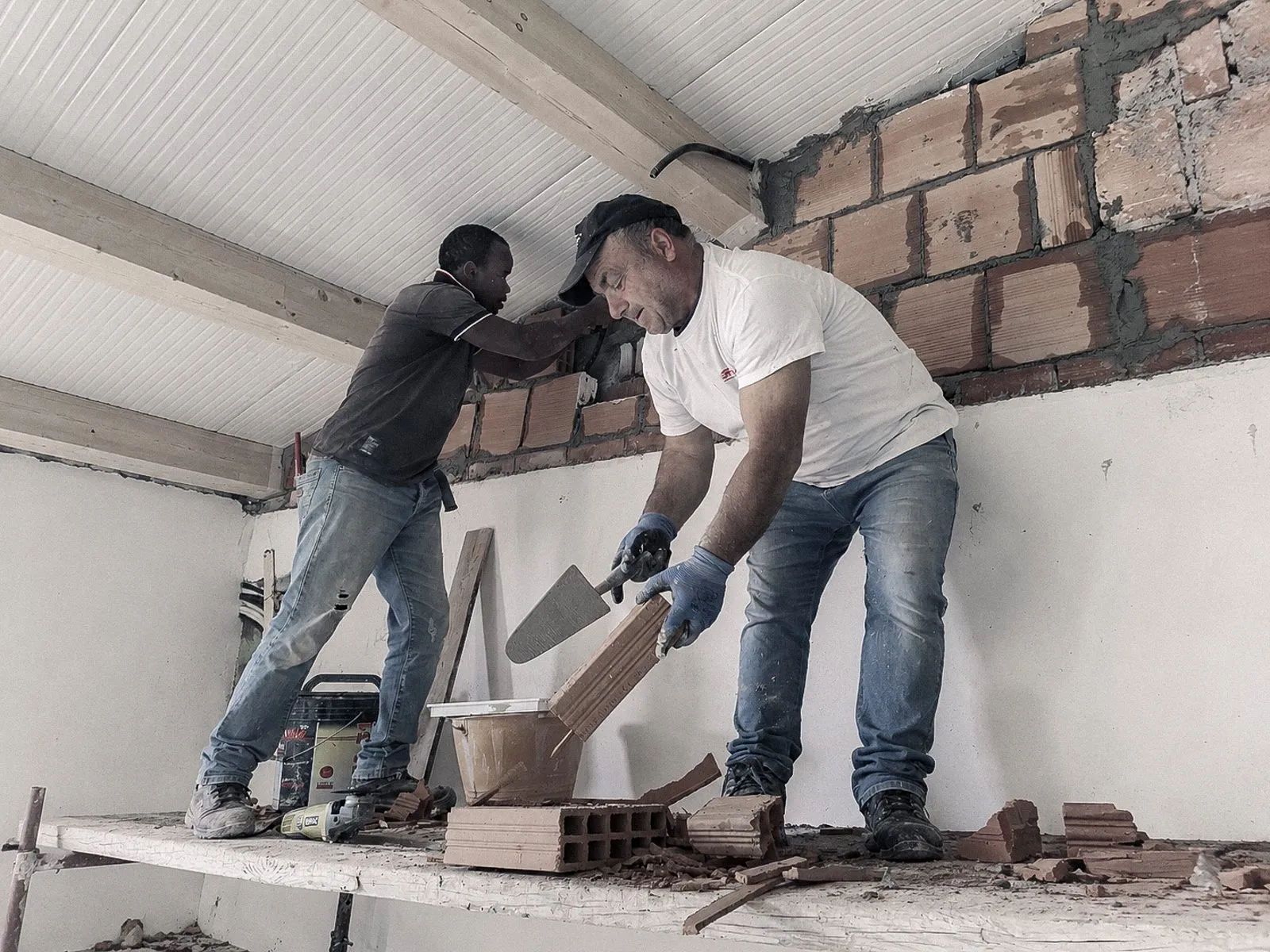Cosmano et Hassan restaurent un mur sur un chantier de Camini