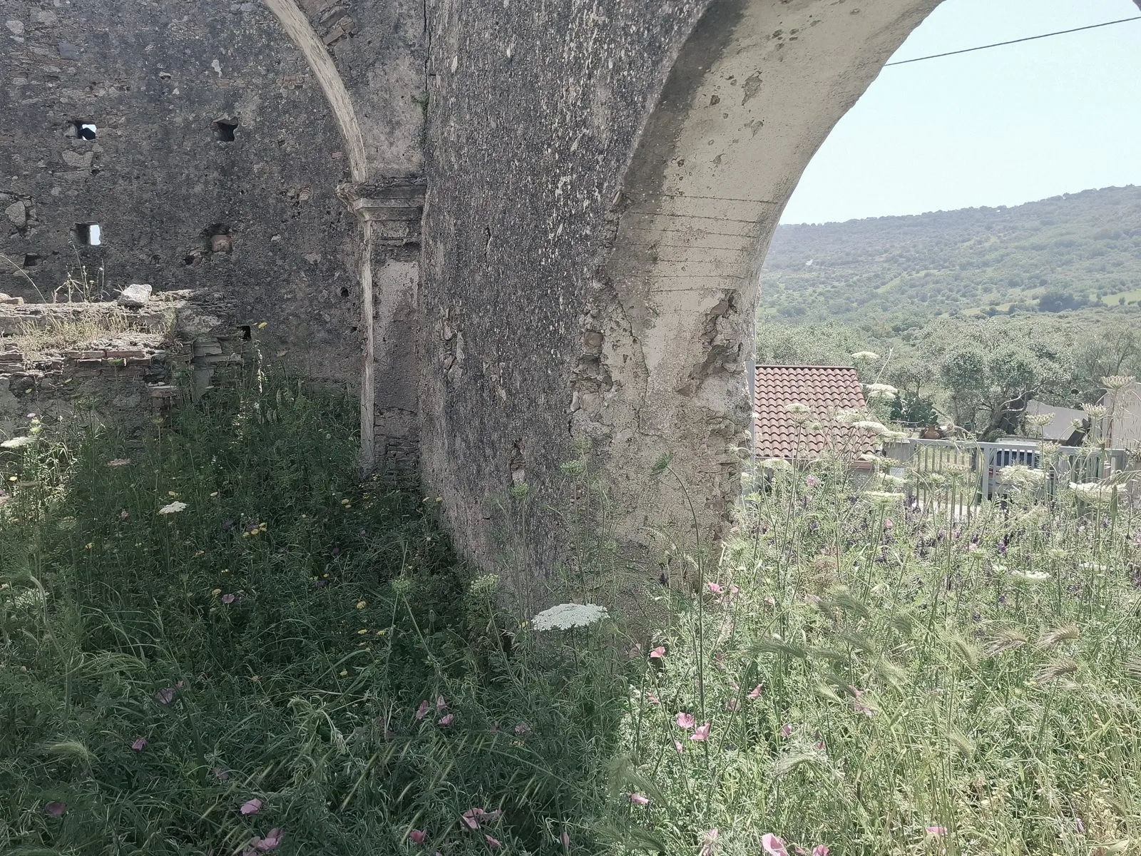 Ruines envahies par les herbes, arche ouverte sur la vallée